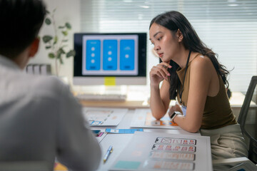 A woman is sitting at a desk with a man in front of her