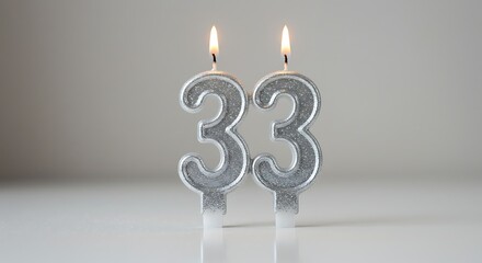 Silver 33 Birthday Candles: Two silver birthday candles, illuminated by a warm and inviting glow, form the number 33, representing a moment of celebration, reflection, and the passage of time.