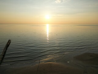 Serene Sunset over the Calm Ocean: A breathtaking scene unfolds as the sun dips towards the...