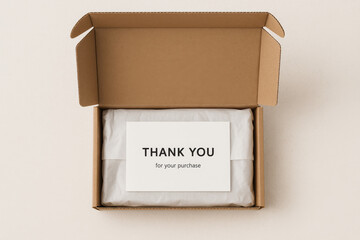 Minimalist cardboard box opened to reveal white tissue-wrapped contents and a thank you note card, styled on a light neutral background for unboxing or e-commerce packaging themes