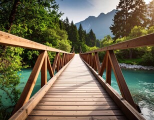 Obraz premium Perspective view of a wooden footbridge crossing a tranquil turquoise river, leading into a lush, sunlit forest with mountains.