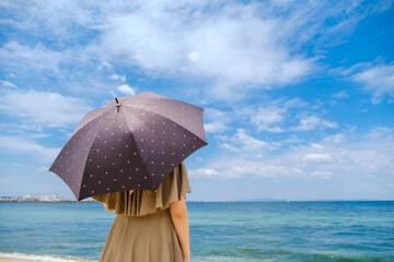 日傘をさして海を眺める女性