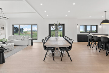 Large, open living room with a long dining table and black chairs