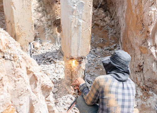 The worker is cutting rebar inside the concrete pile using a gas torch.