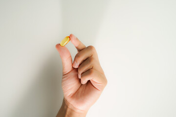 Male hand holding Fish oil capsules with omega 3, omega 9, vitamin D, vitamin E, Cod liver oil