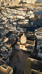 Aerial View of a Historic City: A stunning aerial perspective reveals an ancient cityscape, showcasing the intricate layout of buildings with a captivating view of the sea. Monopoli, Puglia