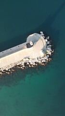 Coastal Fortress: An aerial vista unveils a sturdy, ancient structure, embraced by the shimmering aquamarine waters and the stoic sentinels of rock and water.