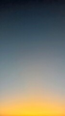 A vertical gradient sky, transitioning from dark blue to vibrant orange and yellow, with a subtle star or planet visible, capturing the serene beauty of dawn.