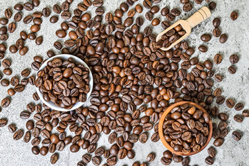 Top view of roasted coffee beans on little or small white plate, wooden bowl And scoop. scattered...
