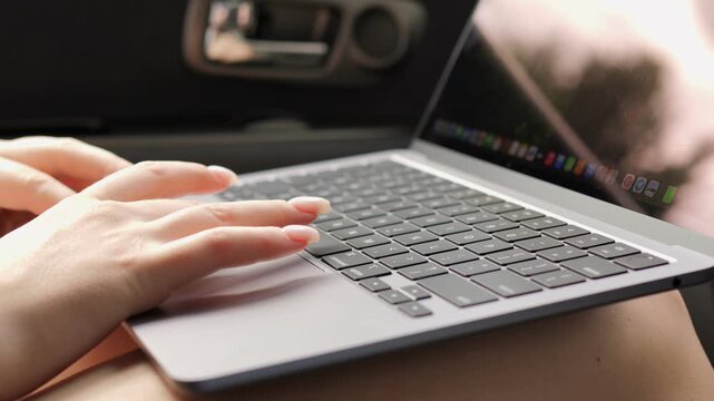 Person is typing on a laptop. The laptop is open and the screen is on. The person is using the keyboard to type