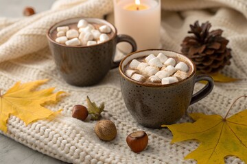 Enjoying hot chocolate with marshmallows on a cozy fall evening by candlelight