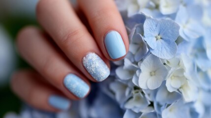 A woman's hand holding a blue manicure with white flowers on it