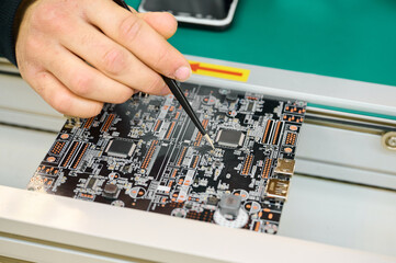 Technician working on a circuit board in a high-tech electronics lab during daytime