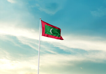 Maldives flag is waving on a tall flagpole among the clouds. Maldives national flag for...