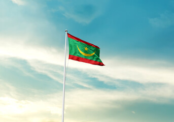 Mauritania flag is waving on a tall flagpole among the clouds. Mauritania national flag for independence day.