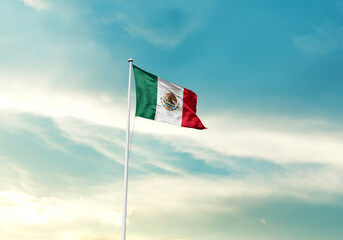 Mexico flag is waving on a tall flagpole among the clouds. Mexico national flag for independence day.