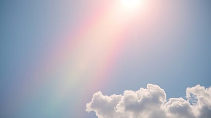 A bright rainbow appears in the blue sky surrounded by beautiful white clouds.