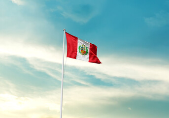 Peru flag is waving on a tall flagpole among the clouds. Peru national flag for independence day.
