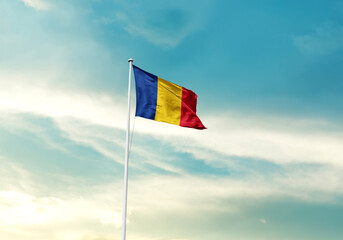 Romania flag is waving on a tall flagpole among the clouds. Romania national flag for independence day.