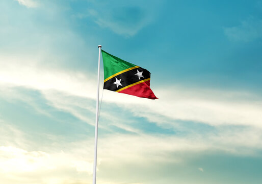 Saint Kitts and Nevis flag is waving on a tall flagpole among the clouds. Saint Kitts and Nevis national flag for independence day.