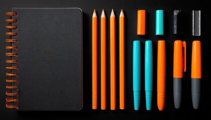 Fototapeta premium Black notebook and assorted orange and teal stationery items on a dark surface