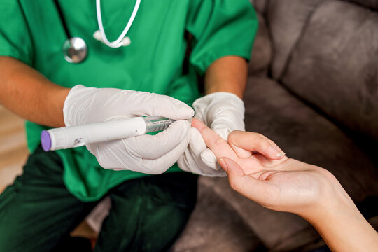Healthcare Professional In Gloves Using Insulin Pen On Patient's Finger For Diabetes Check - Powered by Adobe
