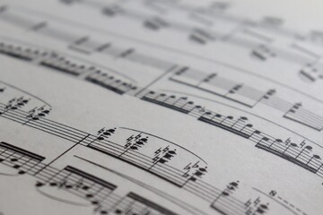 A sheet with a musical partition. Musical notes on a sheet of music paper. Music notes as background with a close-up view. Vintage music partition.