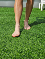 Barefoot walking on artificial grass in a sunny outdoor space during the day concept