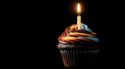 A beautifully decorated chocolate cupcake with a lit candle on top, set against a black background