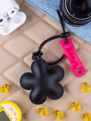 Close-up of a black leather bag charm in the shape of a funny flower on a table.