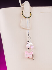  Close-up of a cute phone charm featuring a playful cat-shaped pendant adorned with tiny beads  on...