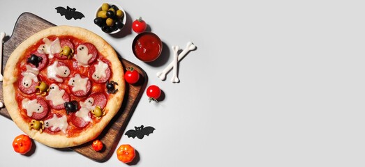 Tasty Halloween pizza, ingredients and decorations on light background with space for text