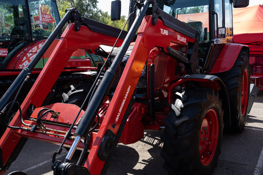 Omsk, Russian Federation - July 30, 2025: Red agricultural tractor with front loader attachment on display at outdoor event, showcasing modern farming equipment and technology