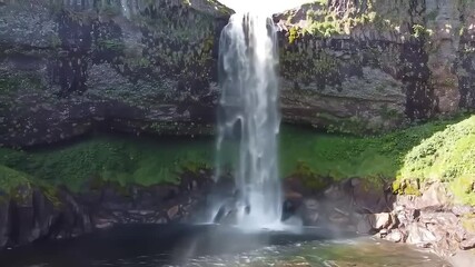Majestic waterfall plunges, green cliff backdrop