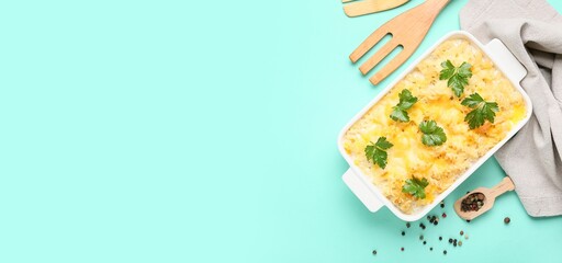 Baking dish of tasty pasta with cheese on turquoise background with space for text