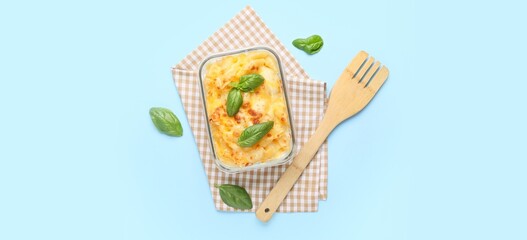 Baking dish of tasty pasta with cheese on blue background