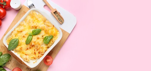 Baking dish of tasty pasta with cheese on pink background with space for text