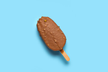 Delicious chocolate covered ice cream on stick against blue background