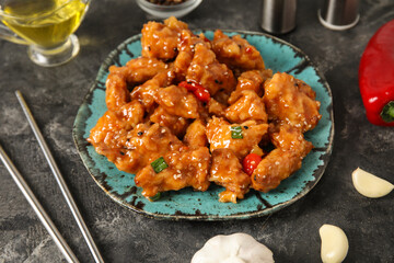 Tasty sweet and sour chicken in plate with spices on grey background, closeup