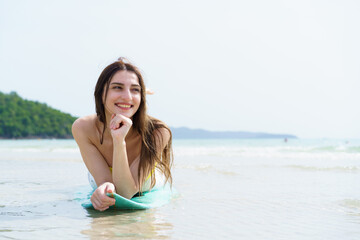 Smiling woman poses with surfboard on a bright beach day.
