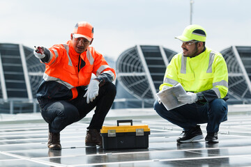 Electrical engineers inspecting and installing a solar panels on the building rooftop.
