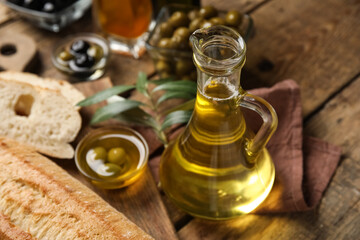 Jug of fresh olive oil on wooden background