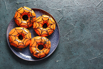 Plate of tasty donuts for Halloween on black background