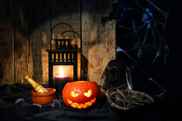 Halloween composition with jack-o-lantern, mortar, pestle and skull on wooden table