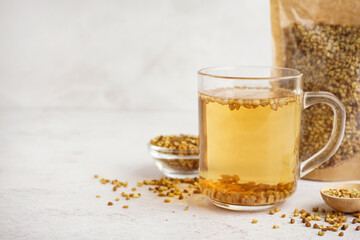 Glass cup of fresh buckwheat tea on light background, closeup