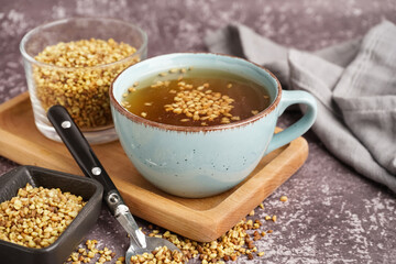 Cup of fresh buckwheat tea on grey grunge background, closeup
