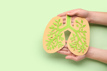 Female hands with paper lungs on green background