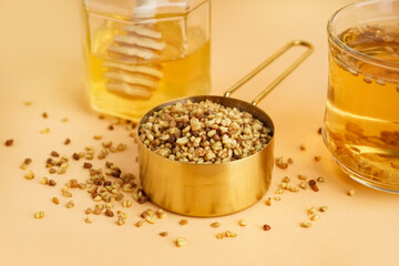 Glass cup of fresh tasty buckwheat tea and honey on beige background, closeup