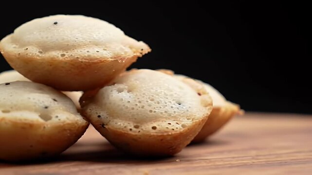Delicious Appam Cakes Stacked on Wooden Table with Dark Backdrop Perfect for Bakery Pastry Promotion Close Up Studio Shot Featuring Golden Brown Edges and Porous Texture Symbolizing Culinary Delights