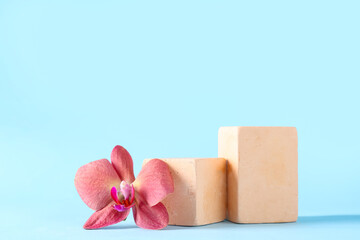Decorative podiums with beautiful orchid flower on blue background
